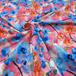Digital bedruckter Baumwolljersey mit floralen Motiven in kräftigem Blau, Rosa und Rot – elastischer Stoff für Nähprojekte, erhältlich bei Stoffrestposten.