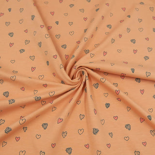 Jersey Stoff in Pfirsich mit kleinen Herz-Motiven in Rosa und Schwarz – elastischer Baumwolljersey für Kinder- und Damenkleidung, erhältlich bei Stoffrestposten.