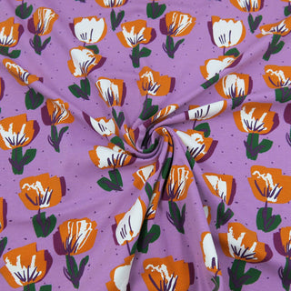 Fliederfarbener Jersey Stoff mit stilisierten Tulpen in Orange, Weiß und Grün – elastischer Baumwolljersey für Kleidung und Accessoires, verfügbar bei Stoffrestposten.