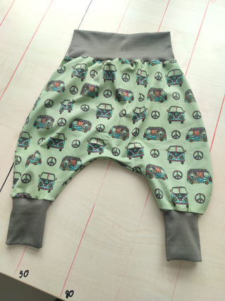 Weicher Jersey Stoff mit farbenfrohem Hippie-Bus-Motiv und Peace-Zeichen auf mintgrünem Hintergrund – elastischer Baumwolljersey für Kleidung und Accessoires, verfügbar bei Stoffrestposten.